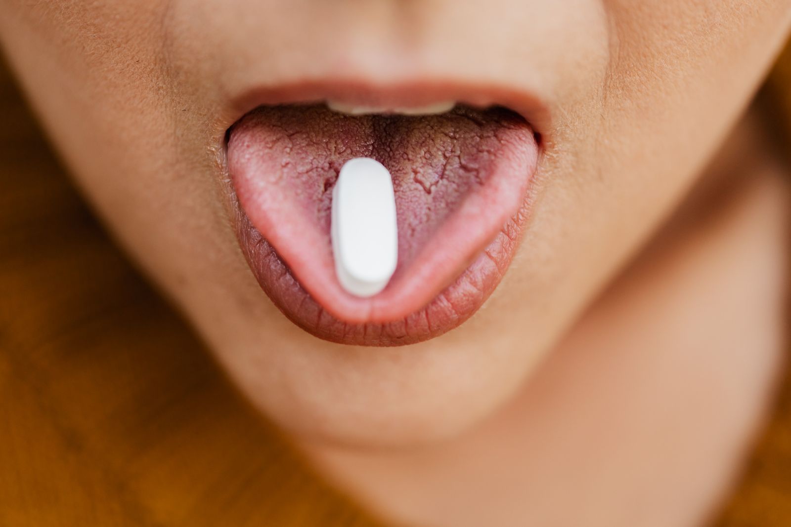 A person taking a tablet with a glass of water, the way a course of antibiotics for a tooth infection gets taken