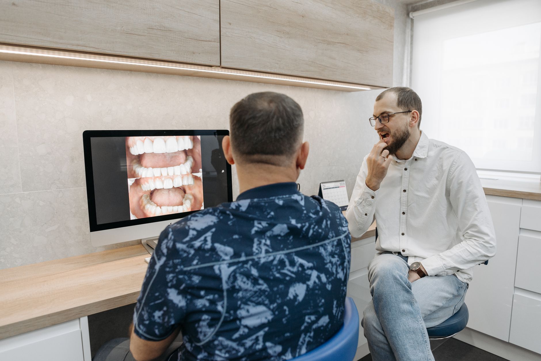 A dentist going through a patient's X-ray, the kind of exam that finds where a tooth abscess is draining from