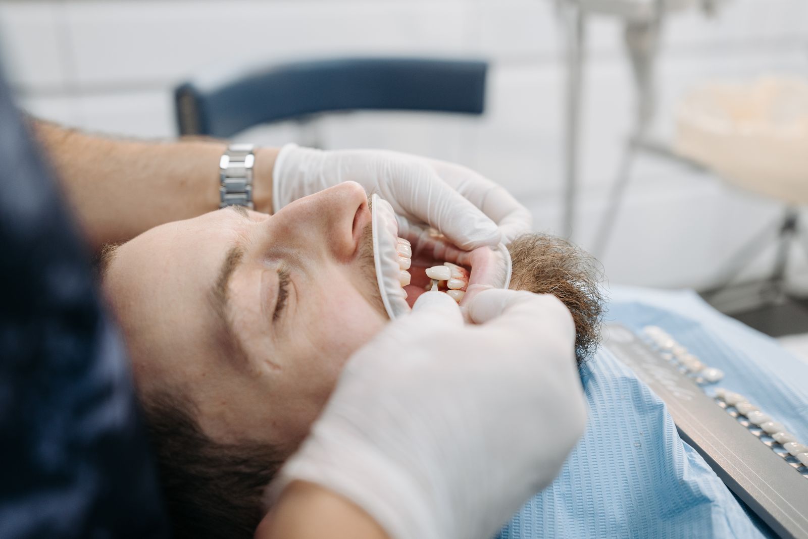 A dentist examining a patient's open mouth, checking a front tooth after a chip
