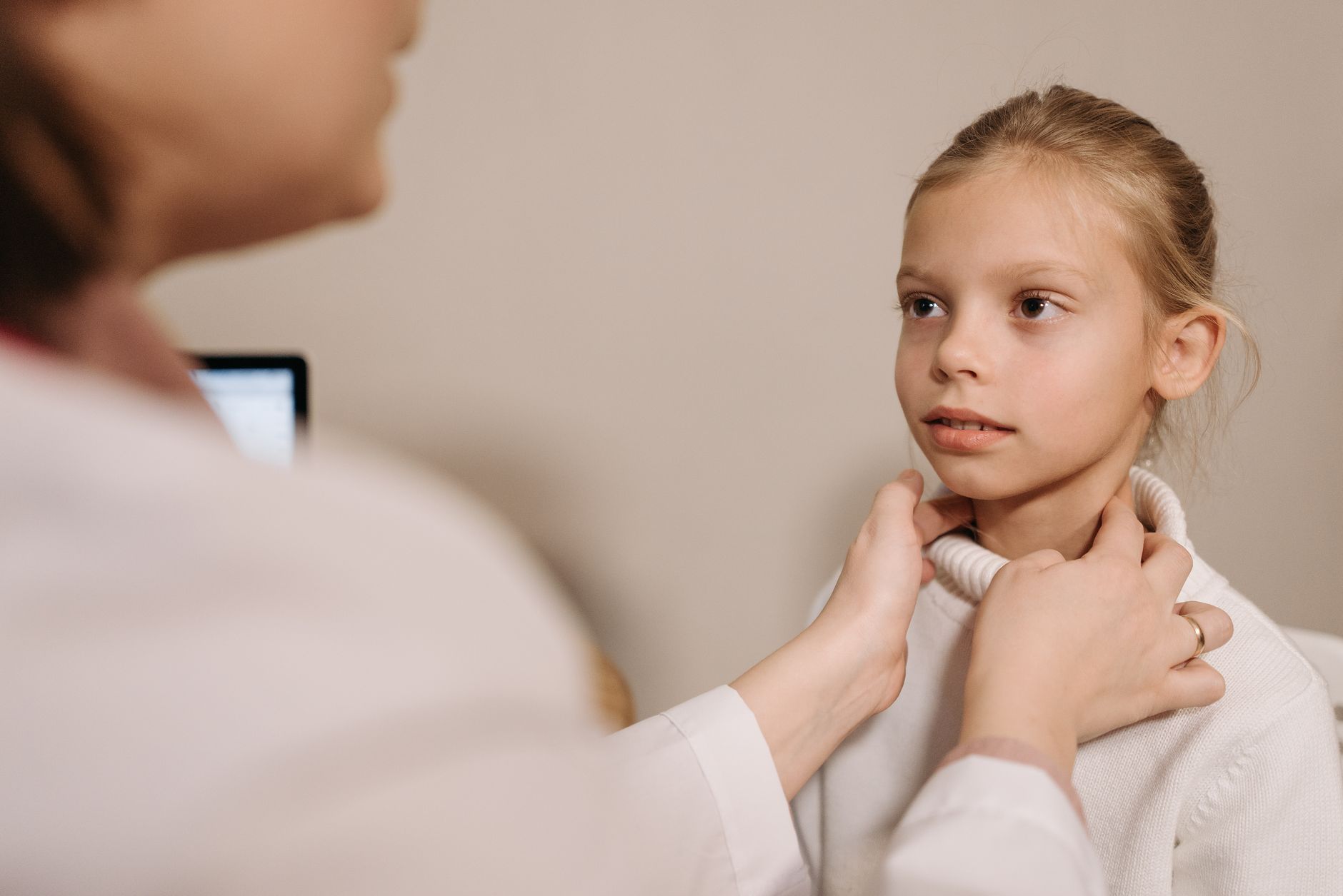 A doctor examining a patient's neck and throat, checking for the swelling that signals a spreading infection