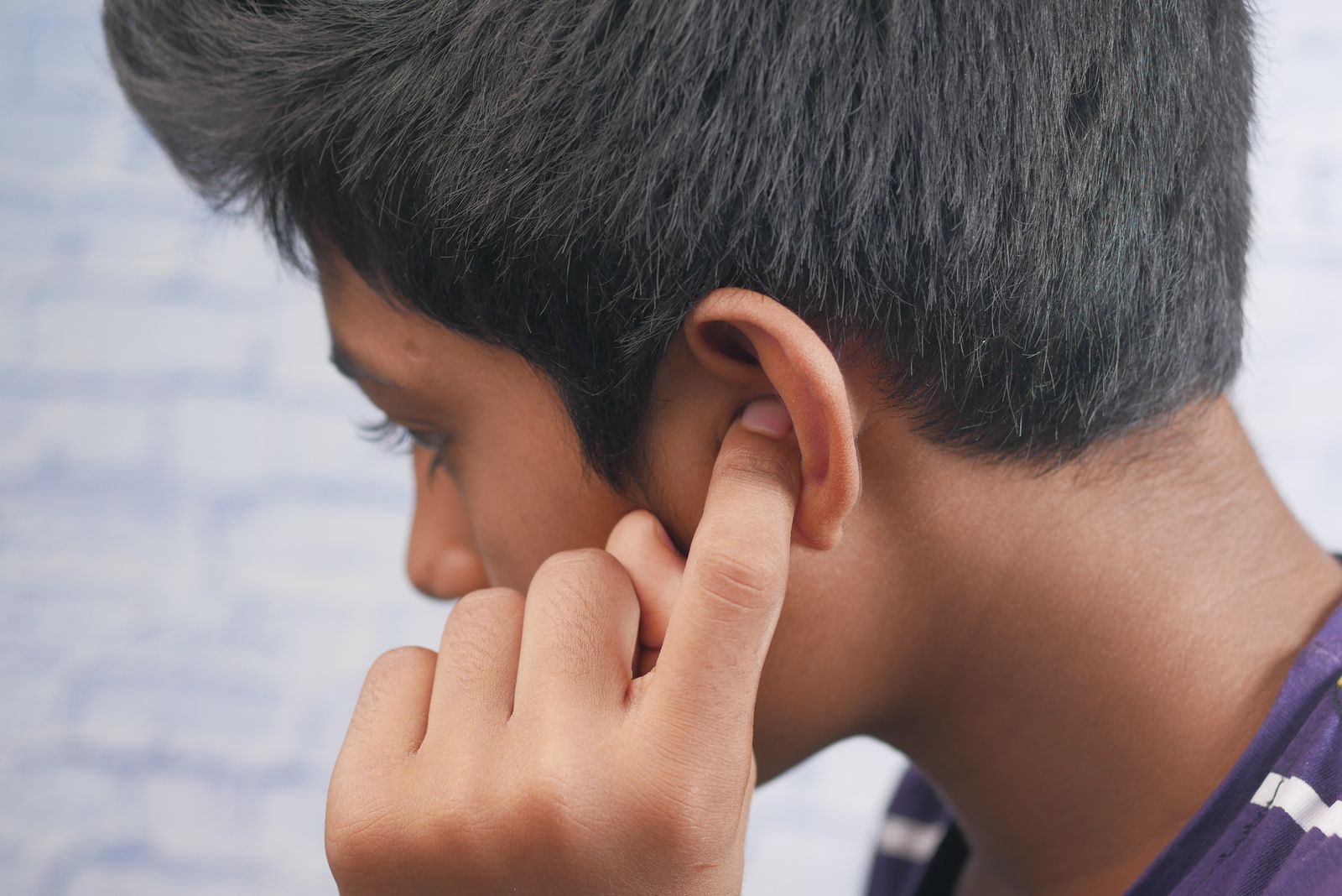 A person holding their ear in discomfort, the kind of ear pain that can start in a back tooth