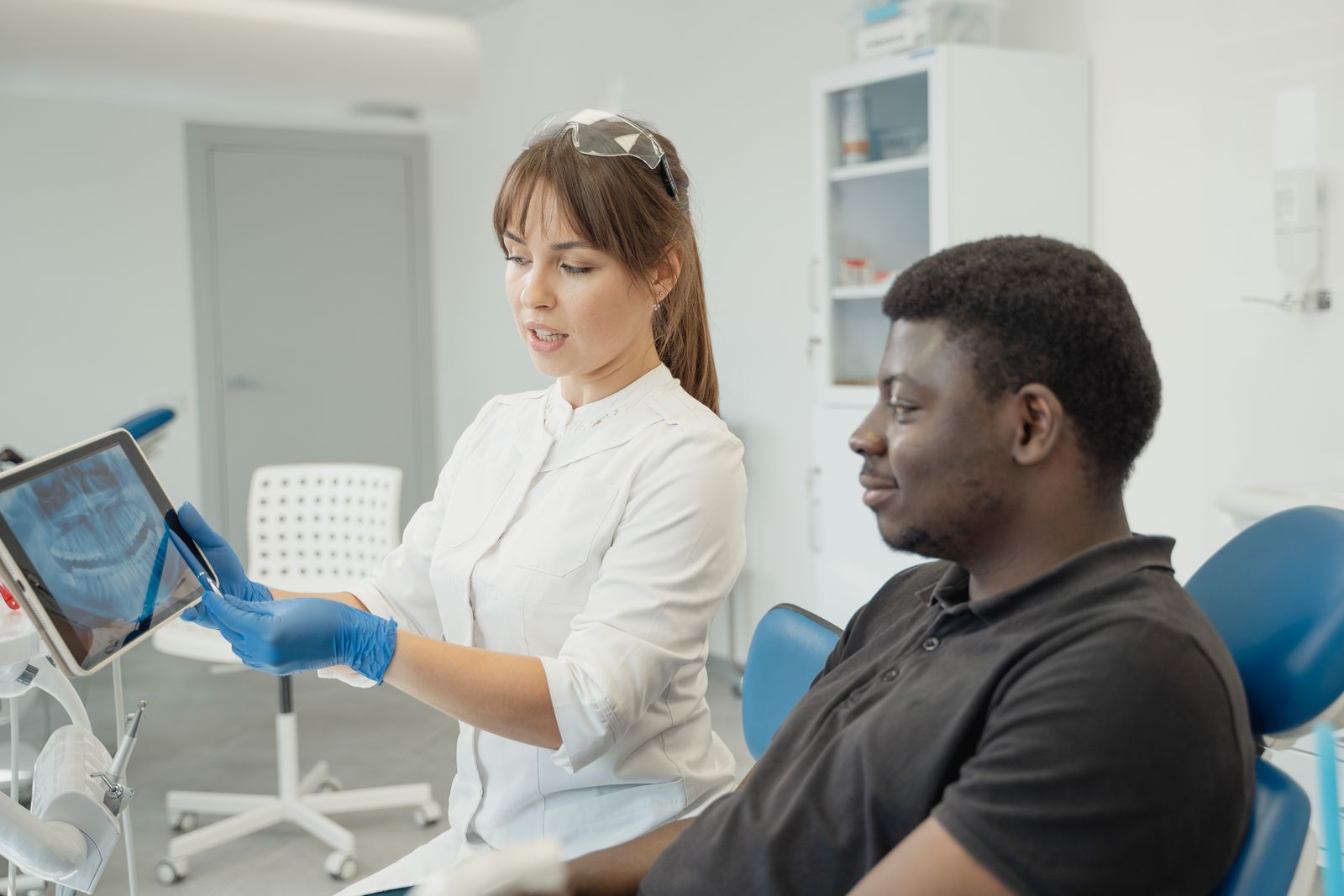A dentist showing a patient a dental X-ray result while discussing redoing a root canal