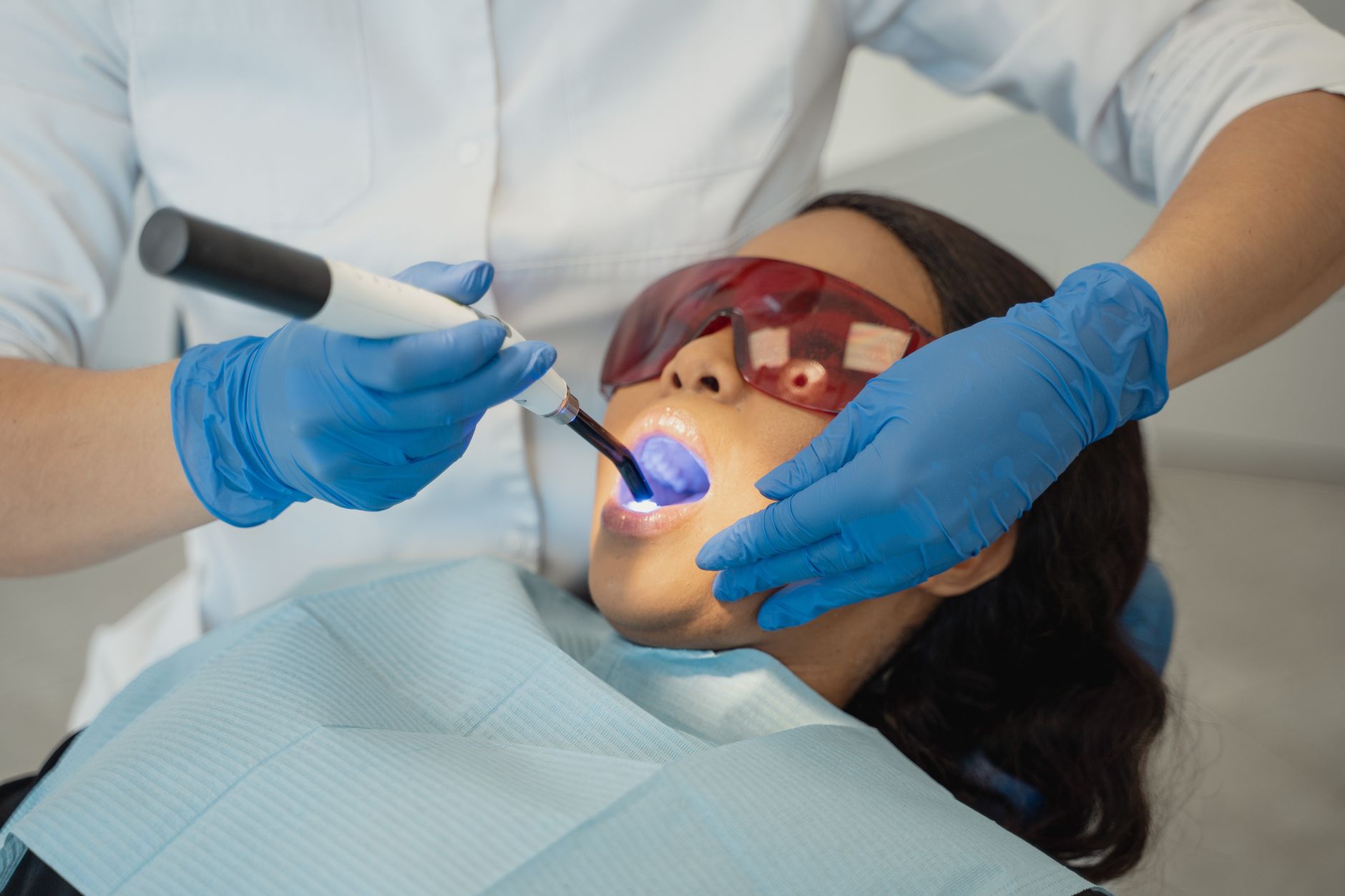 A dentist setting a white filling with a blue curing light