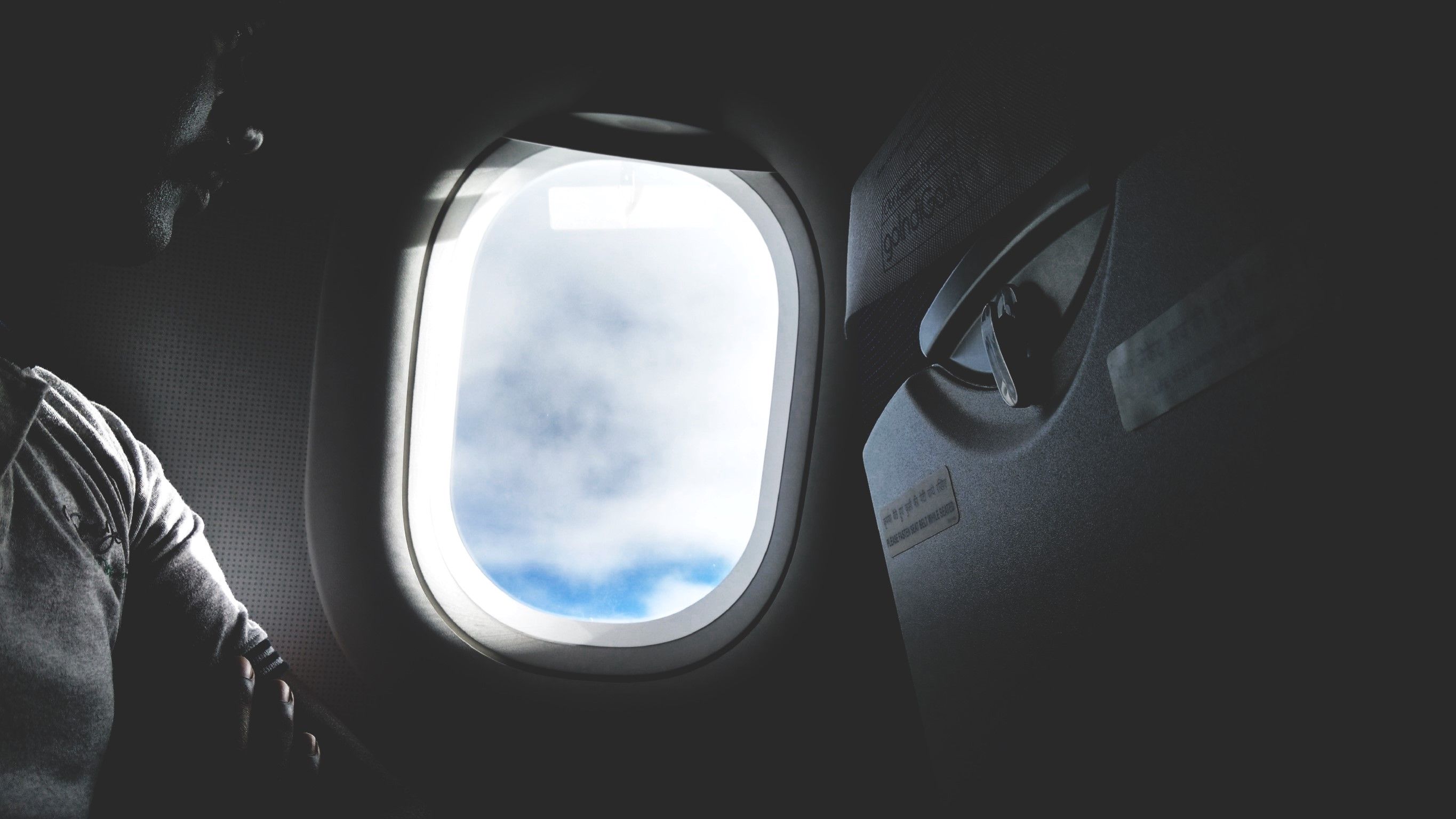 View of the sky and clouds through an open airplane cabin window