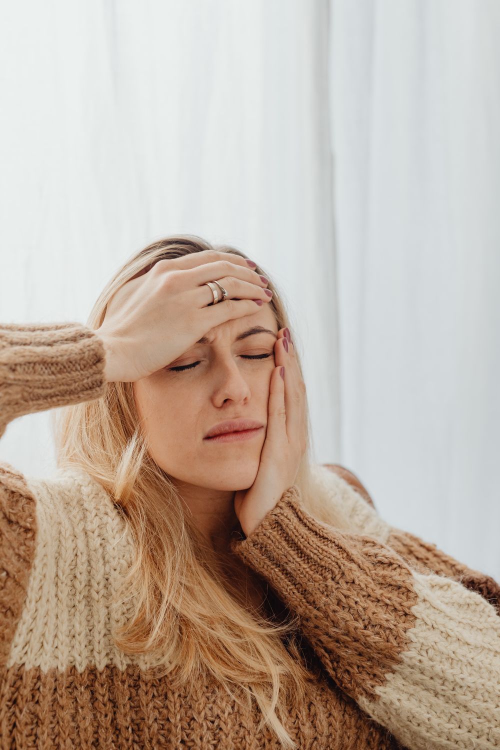 A woman gently pressing her hand to her jaw in discomfort