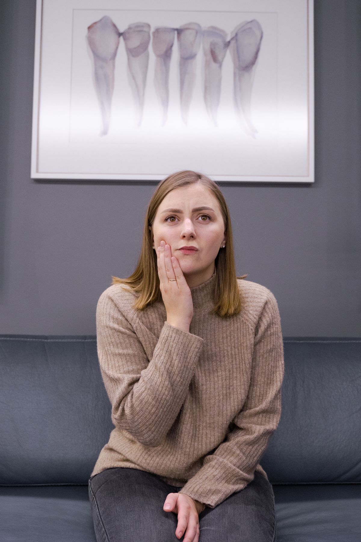 Woman holding her cheek in pain in a dental clinic