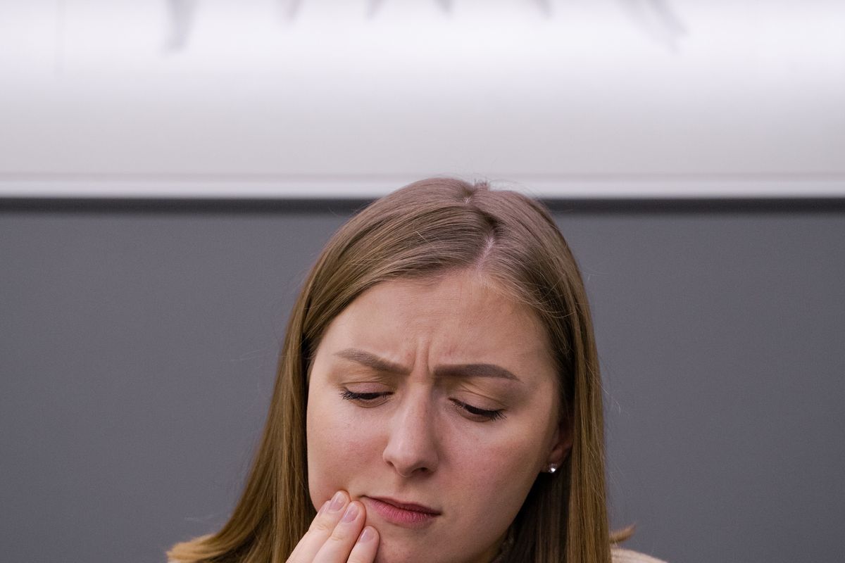 Woman holding her hand to one side of her jaw in discomfort