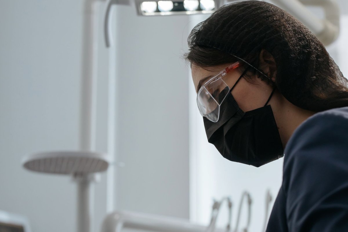 Dentist in mask and safety glasses working in a clinic