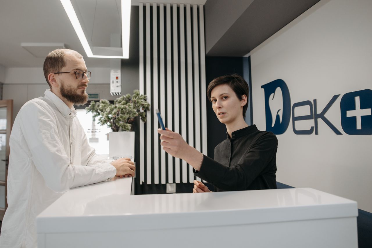 A patient speaking with a receptionist at a clinic front desk