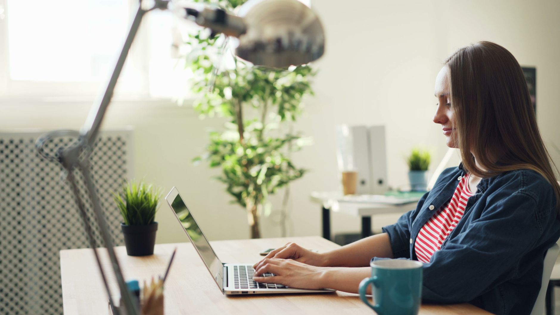 A woman working on a laptop at a desk in a bright office