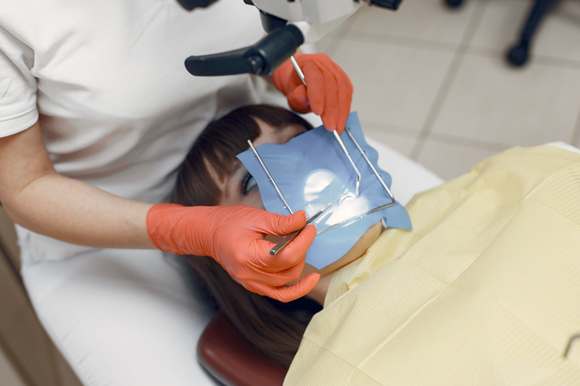 A patient in a dental chair receiving treatment from a dentist using clinical equipment
