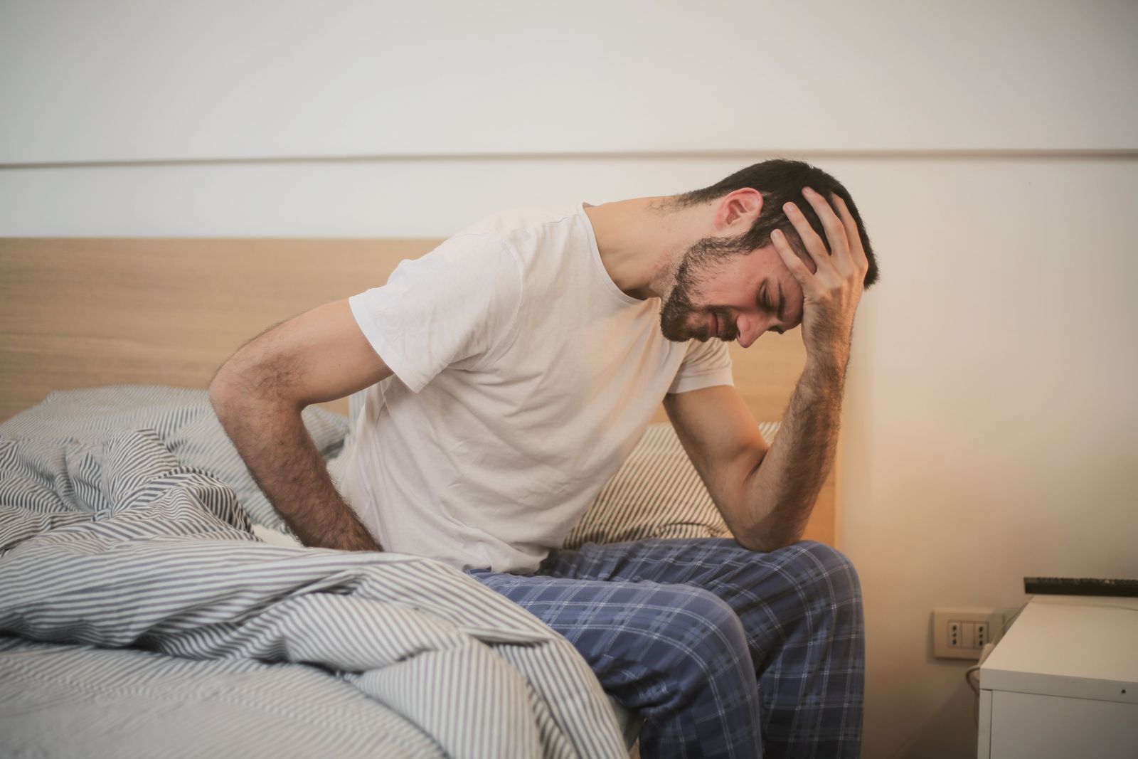 גבר צעיר בבית אוחז את ראשו, ער וכואב