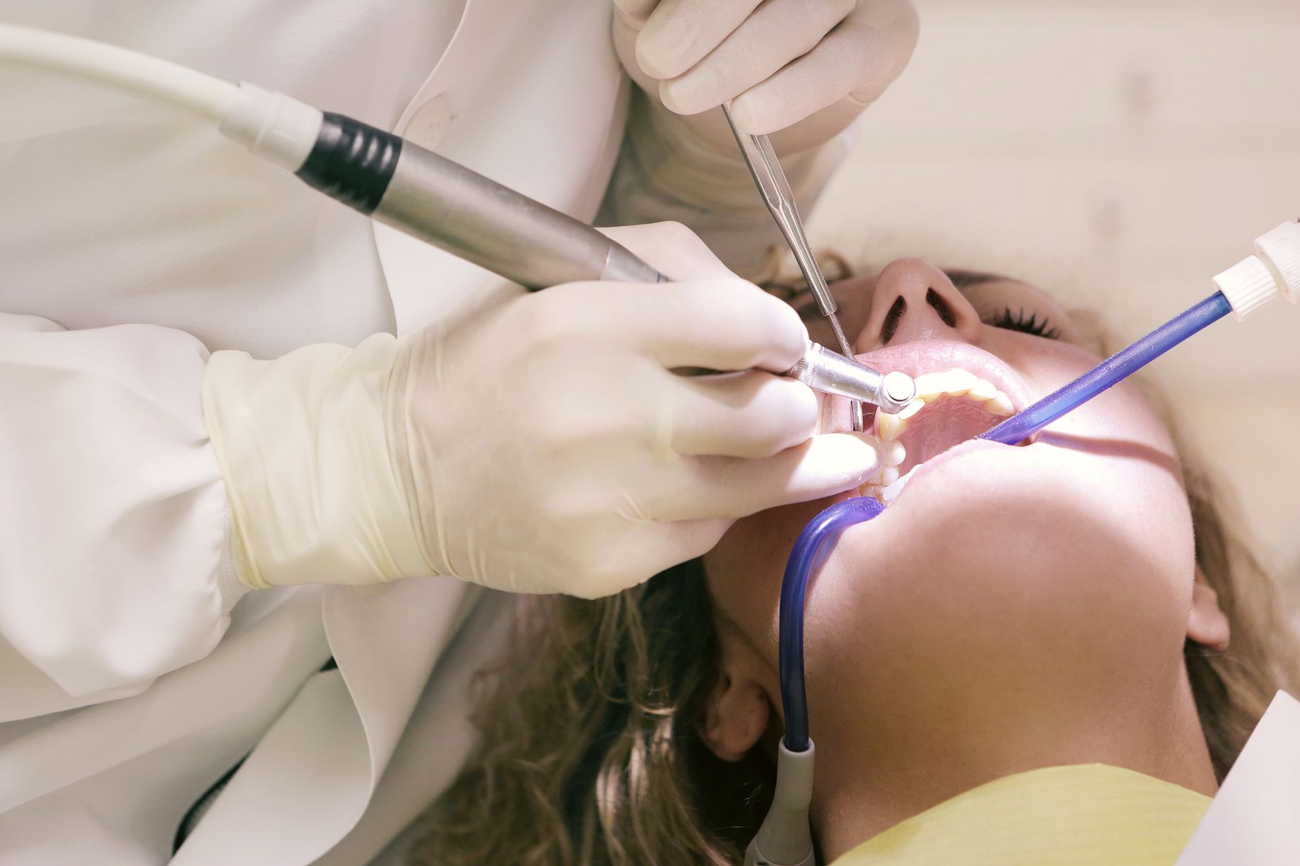 A dentist in gloves using instruments to treat a patient's tooth in a clinic