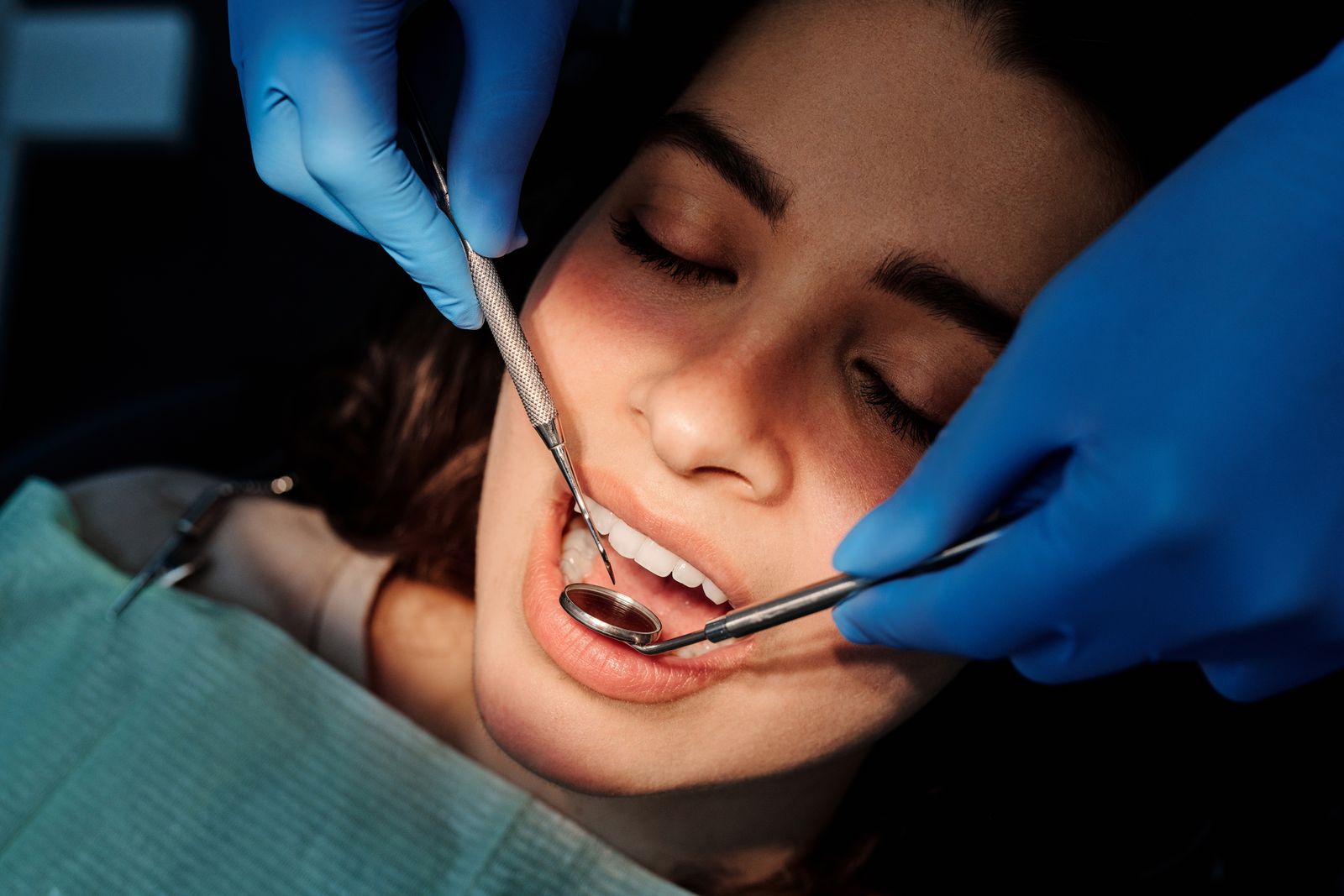 A dentist examining a woman's teeth with a mirror and probe