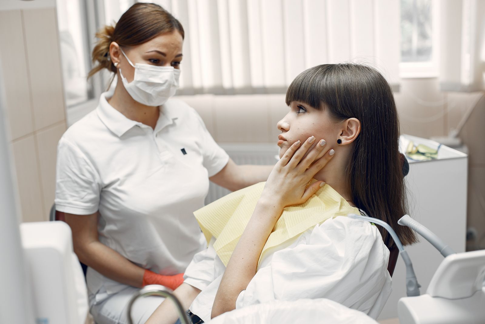 A woman holding her jaw, wincing from a tooth that is sensitive to heat