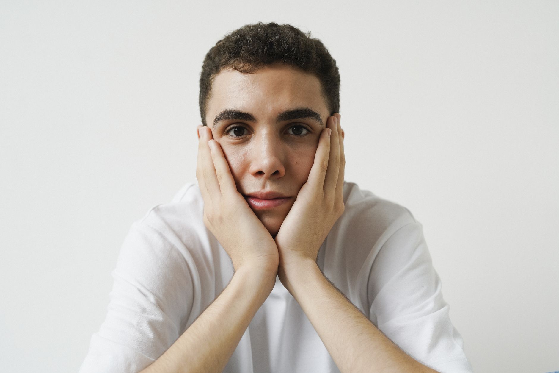 A young man resting his face in his hands, looking weary from lingering tooth discomfort
