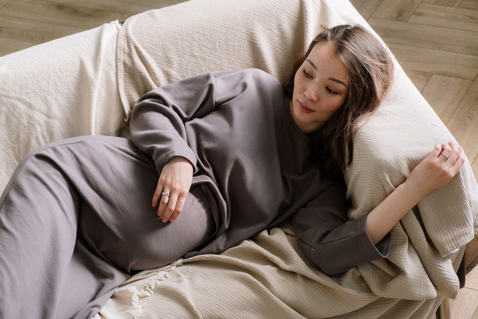 A pregnant woman resting calmly on a couch at home