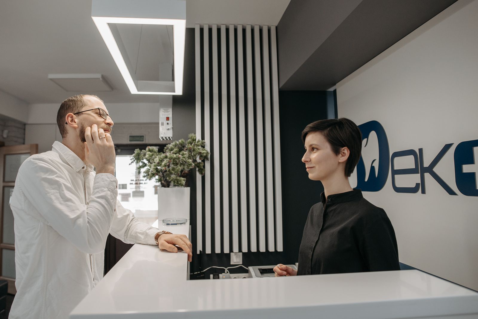 A patient speaking with a receptionist at the front desk of a dental clinic