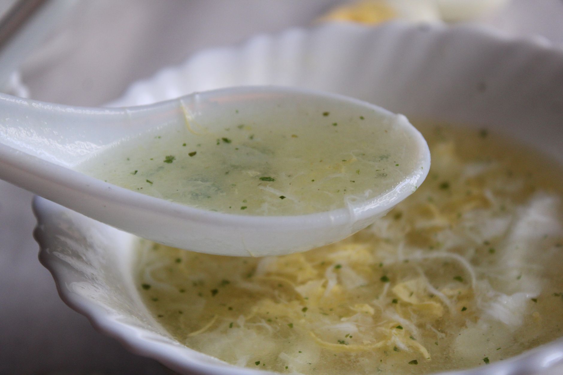 A white bowl of smooth egg drop soup, a soft warm food that suits the first days after a tooth extraction