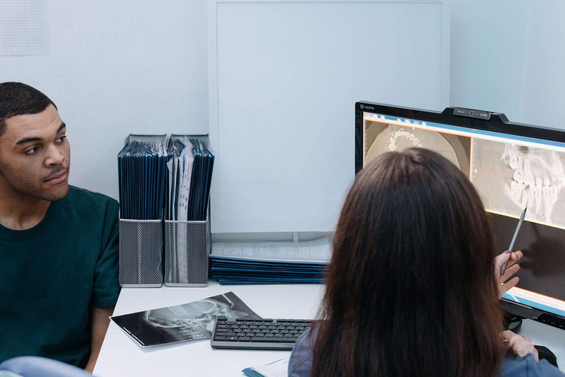 A dentist and patient reviewing a dental X-ray together to decide whether a tooth needs extracting