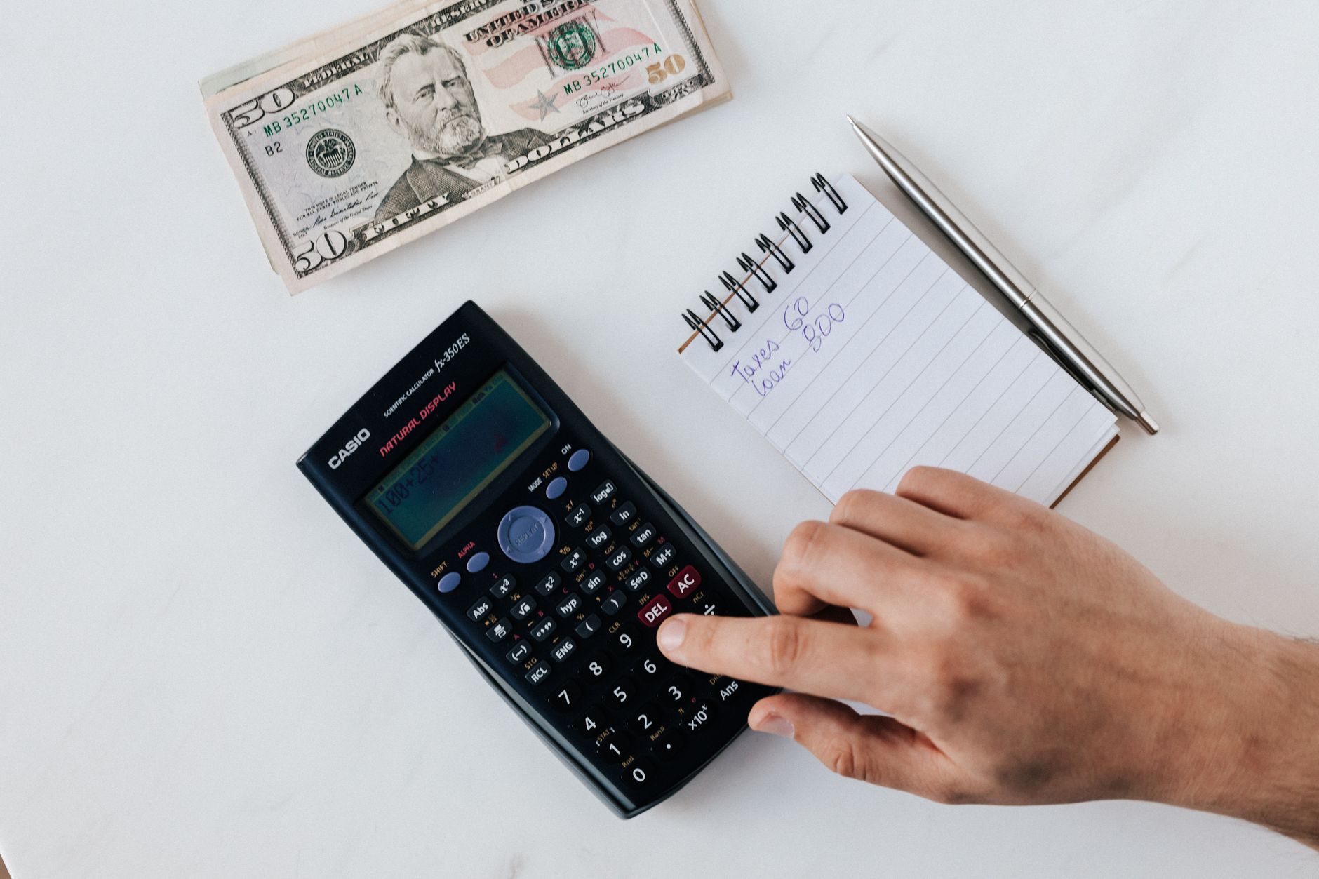 Hands using a calculator to work out a budget on a desk